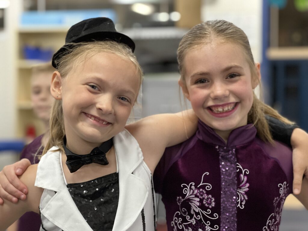 Two girls smiling in dance costumes